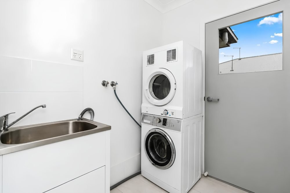 The laundry, with a sink and stacked washer and dryer.