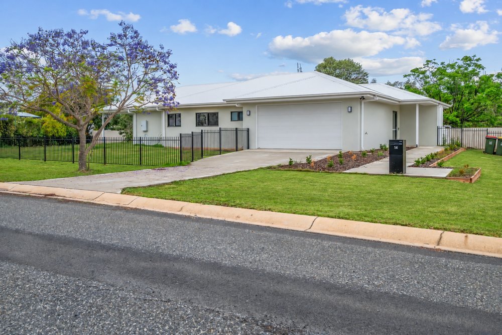 The front of the home: a white single-storey house with a fenced front lawn and a jacaranda tree.