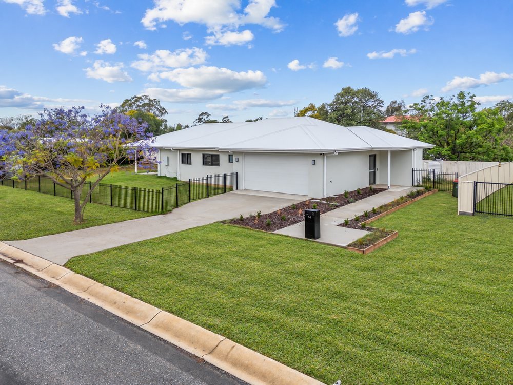 The front of the home: a white single-storey house with a fenced front lawn and a jacaranda tree.