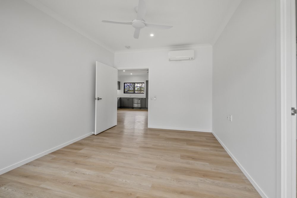 A bedroom with a split-system air conditioner and a doorway to its ensuite.