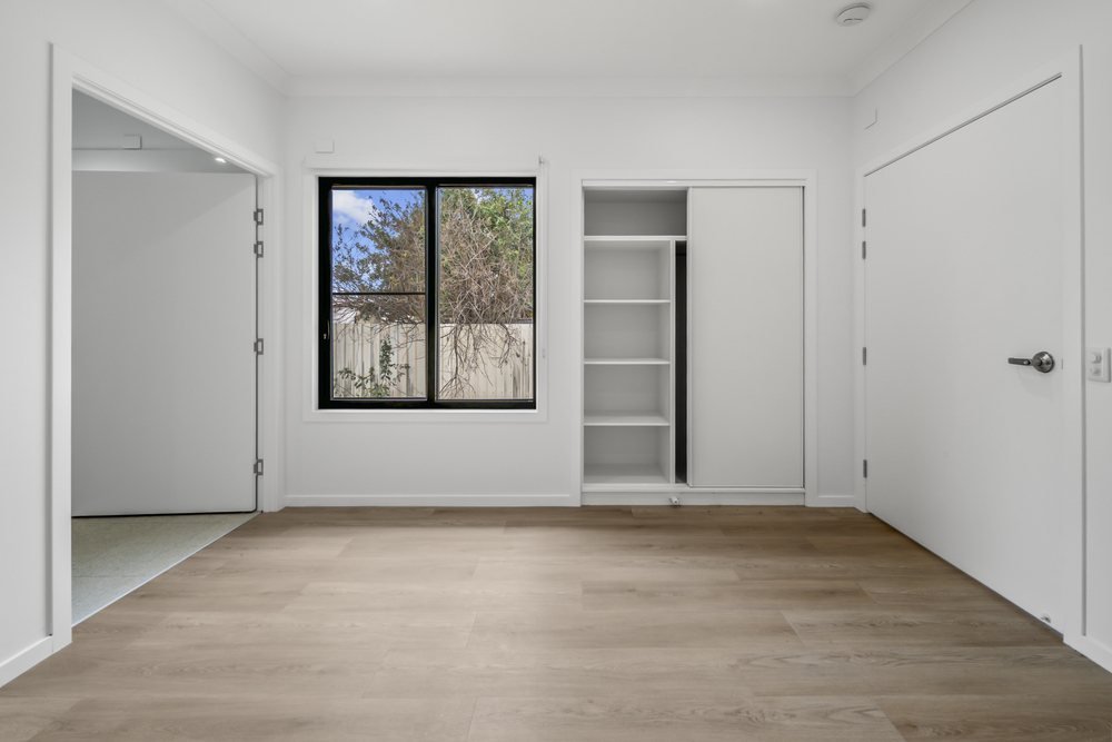The second bedroom, with a split-system air conditioner and its ensuite beyond.