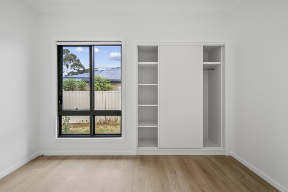 A bedroom with a split-system air conditioner and built-in robes.