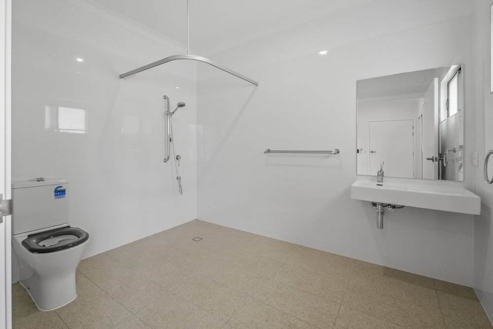 A bedroom with open shelving, a sliding-door wardrobe and a window to the yard.