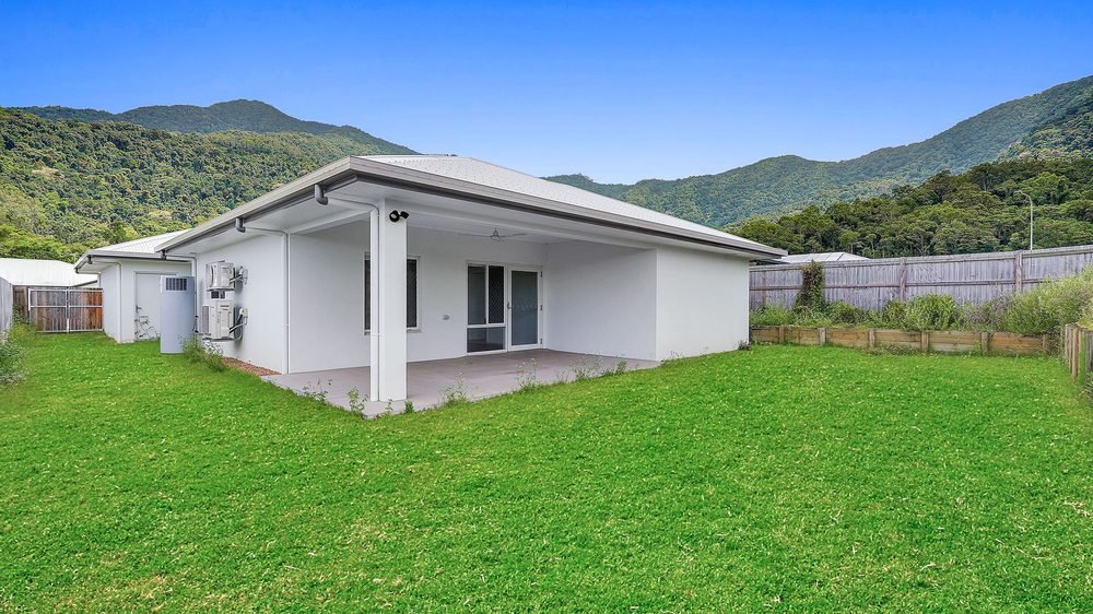 The back of the home: the covered patio and a lawn, with the ranges behind.